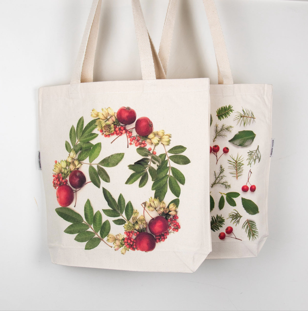 Two tote bags with nature-themed designs hanging on a rack.